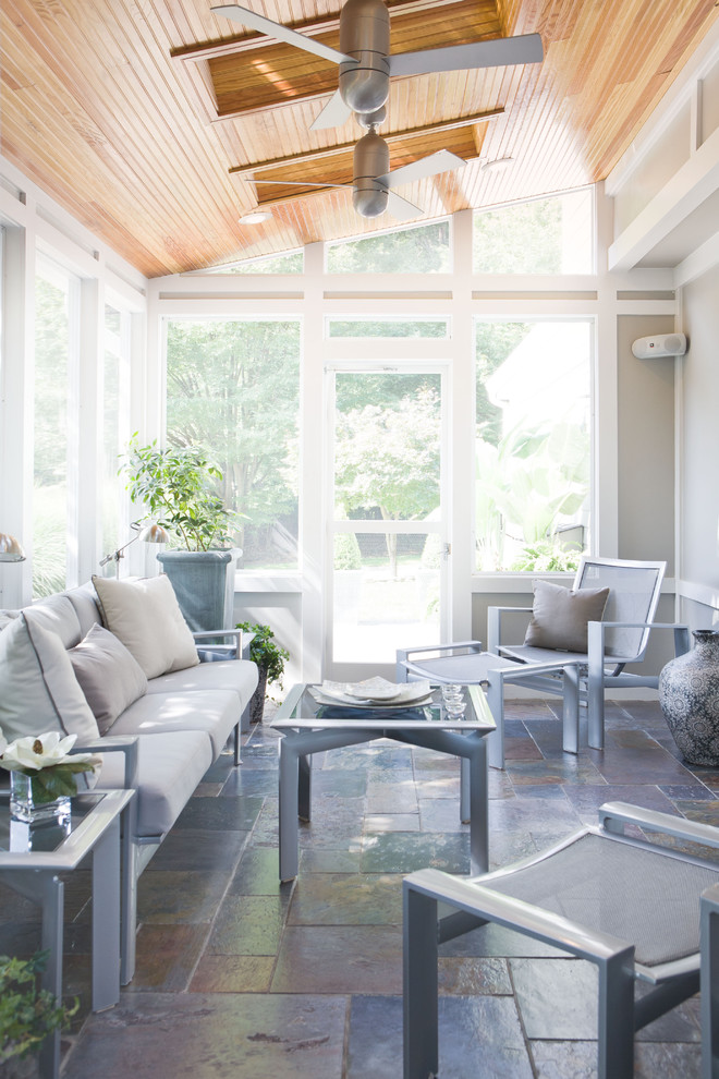 This is an example of a transitional sunroom in DC Metro with a skylight and grey floor.