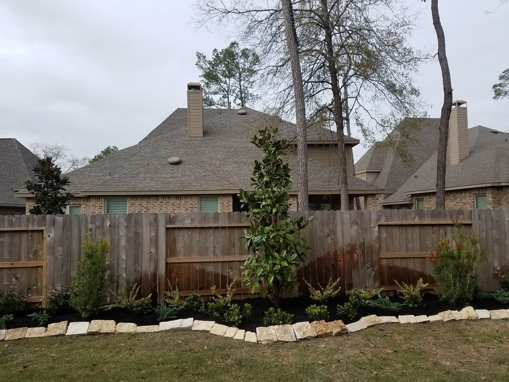 This is an example of a large traditional backyard full sun garden in Houston with natural stone pavers.