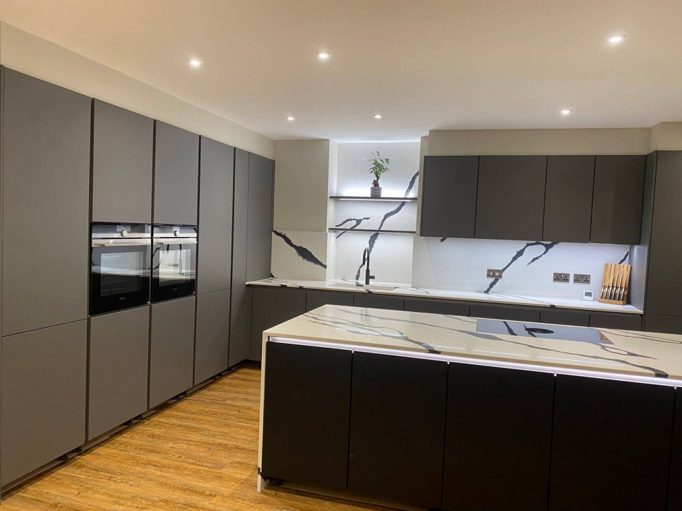 Design ideas for a large modern u-shaped eat-in kitchen in Hertfordshire with an undermount sink, beaded inset cabinets, grey cabinets, quartzite benchtops, multi-coloured splashback, engineered quartz splashback, black appliances, light hardwood floors, with island, brown floor and multi-coloured benchtop.