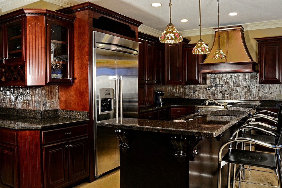 Eat-in kitchen - traditional l-shaped eat-in kitchen idea in Phoenix with raised-panel cabinets, dark wood cabinets, granite countertops, metallic backsplash, stainless steel appliances and an island