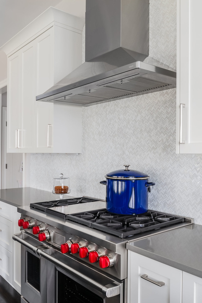 Inspiration for a large transitional l-shaped dark wood floor and brown floor open concept kitchen remodel in Boston with an undermount sink, shaker cabinets, white cabinets, quartz countertops, white backsplash, marble backsplash, stainless steel appliances, an island and white countertops