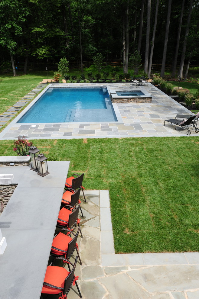 Photo of a large traditional backyard rectangular lap pool in Philadelphia with a hot tub and natural stone pavers.