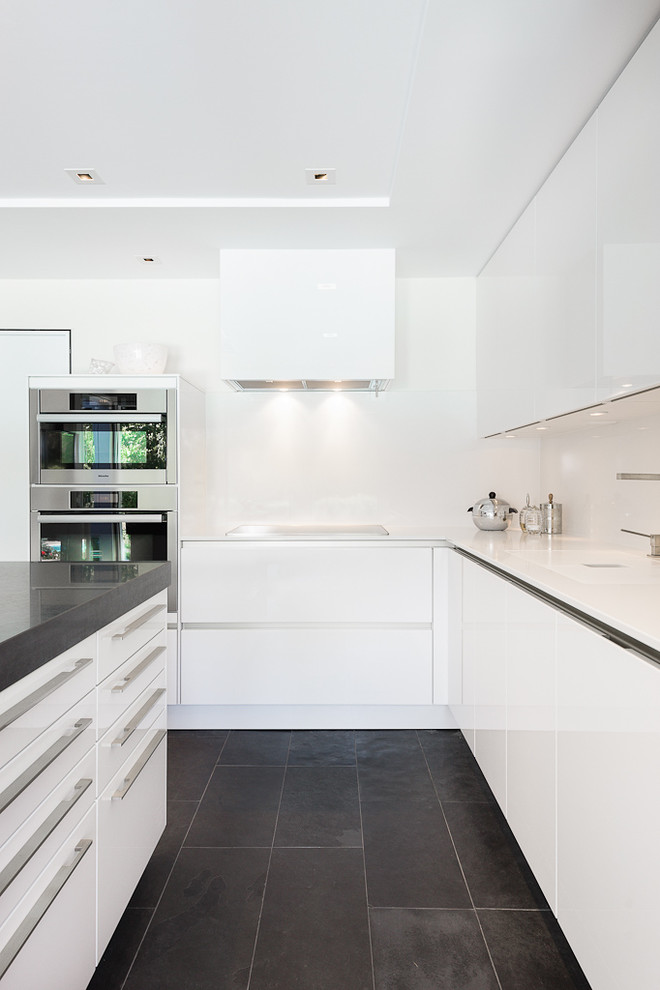 Design ideas for a mid-sized contemporary l-shaped kitchen in Ottawa with flat-panel cabinets, white cabinets, black floor, quartzite benchtops, white splashback, stainless steel appliances, slate floors and with island.
