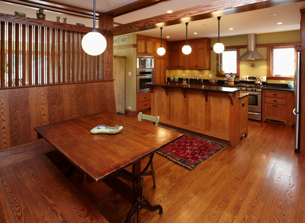 Photo of a traditional u-shaped kitchen in Chicago with stainless steel appliances, a farmhouse sink, recessed-panel cabinets, medium wood cabinets, soapstone benchtops, medium hardwood floors and with island.