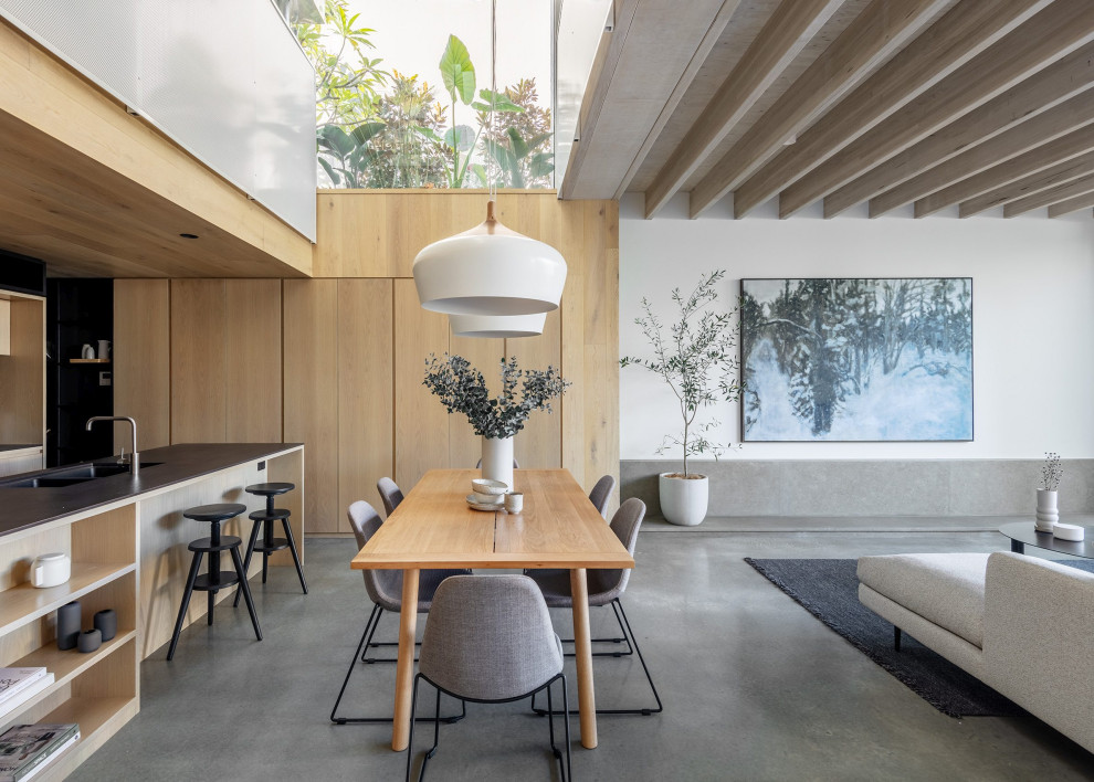 Photo of a modern dining room in Sydney with white walls, concrete floors, grey floor and exposed beam.