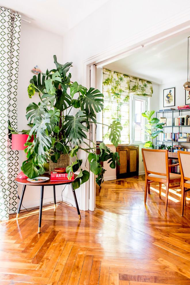 Mid-sized tropical separate dining room in Madrid with white walls, medium hardwood floors and no fireplace.