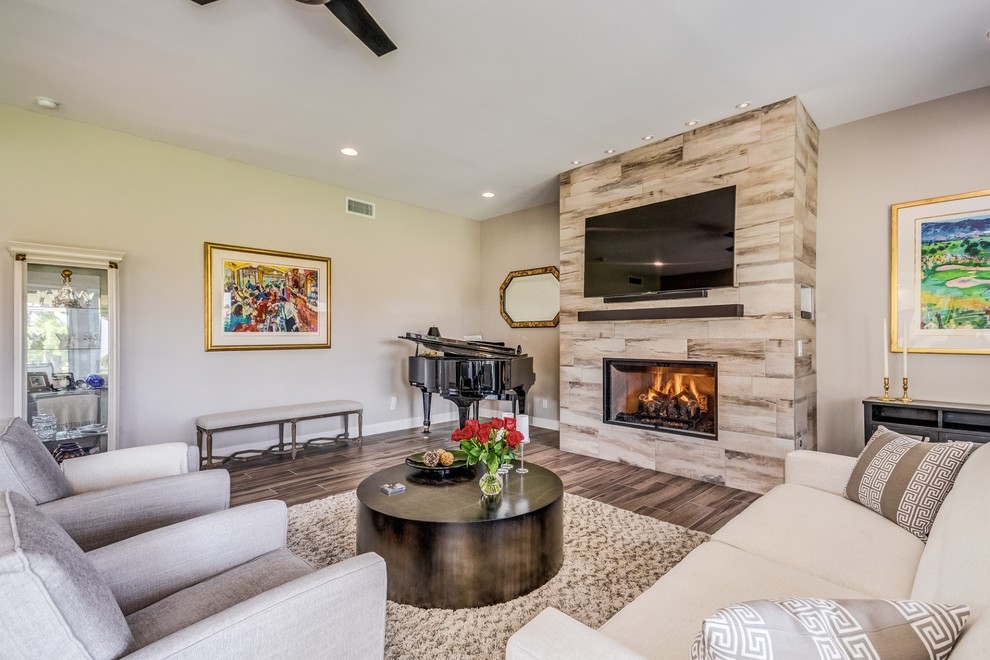 This is an example of a mid-sized contemporary open concept living room in Phoenix with grey walls, porcelain floors, a standard fireplace, a tile fireplace surround, a wall-mounted tv and beige floor.