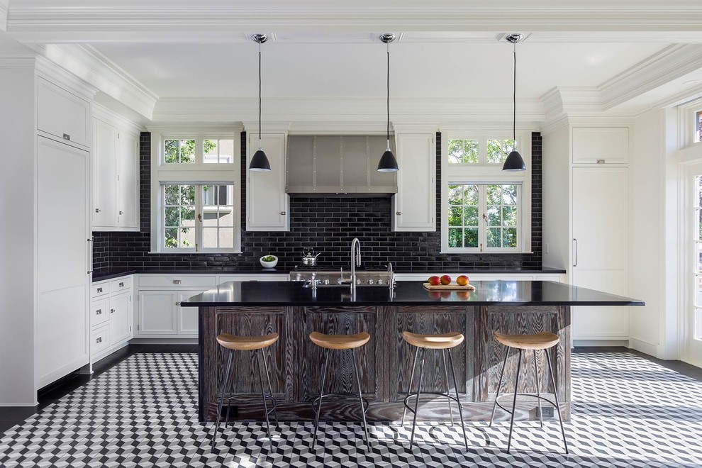 Photo of a traditional l-shaped open plan kitchen in San Francisco with a farmhouse sink, recessed-panel cabinets, white cabinets, black splashback, subway tile splashback, panelled appliances, porcelain floors and with island.