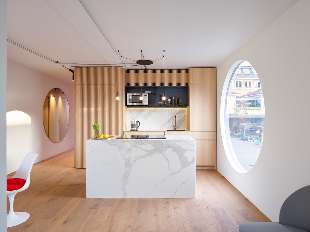 Small contemporary galley eat-in kitchen in Stuttgart with a drop-in sink, flat-panel cabinets, light wood cabinets, marble benchtops, white splashback, marble splashback, medium hardwood floors, with island, brown floor and white benchtop.