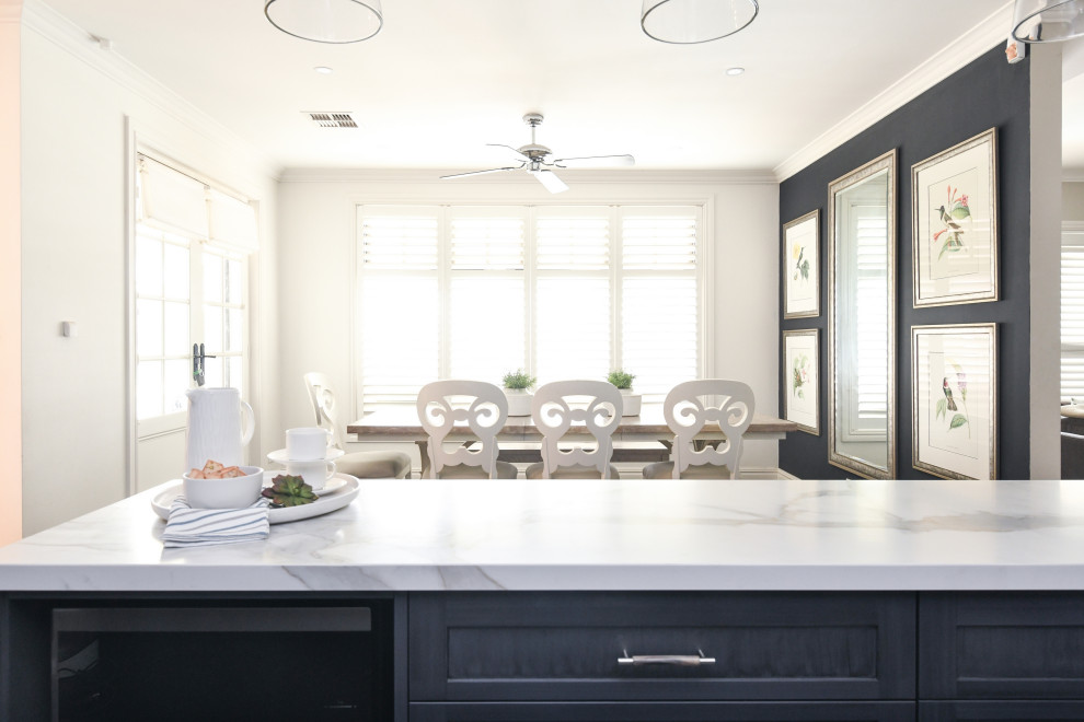 Modern inredning av ett litet u-kök, med en undermonterad diskho, skåp i shakerstil, blå skåp, stänkskydd i porslinskakel, svarta vitvaror, klinkergolv i porslin, en halv köksö och svart golv