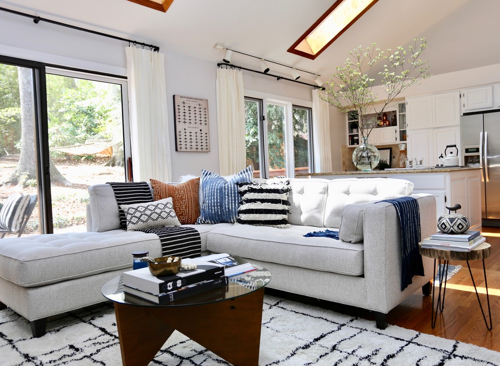 Inspiration for an eclectic open concept family room in Other with white walls and medium hardwood floors.