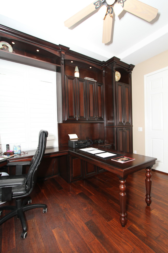 Traditional study room in Orange County with beige walls, dark hardwood floors, a built-in desk and brown floor.