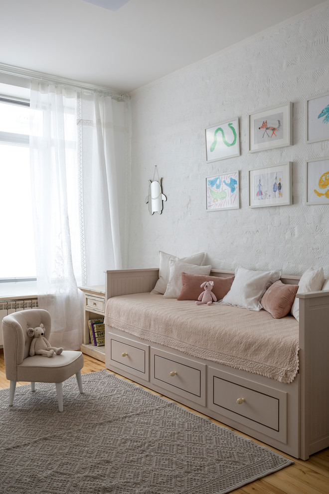 Photo of a transitional nursery for girls in Moscow with white walls, medium hardwood floors and brown floor.