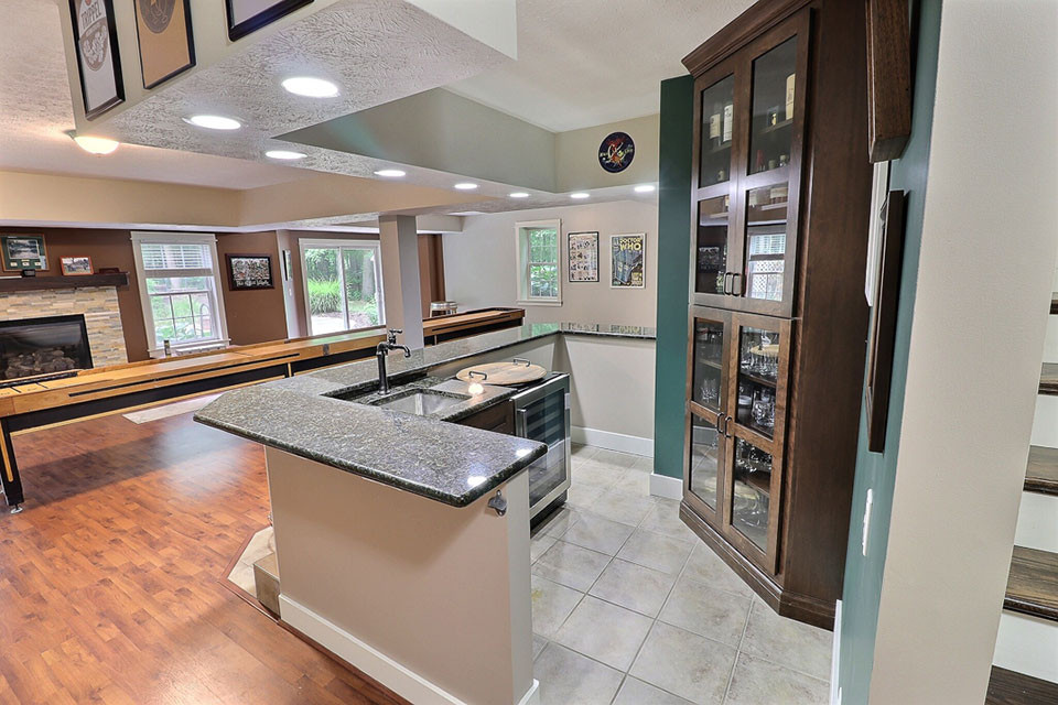 Exempel på en mellanstor klassisk flerfärgade u-formad flerfärgat hemmabar med vask, med travertin golv, beiget golv, en undermonterad diskho, skåp i shakerstil, skåp i mörkt trä, granitbänkskiva och grönt stänkskydd