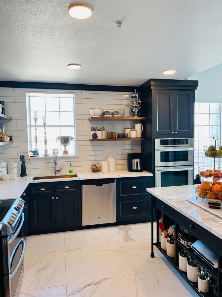 Photo of a mid-sized eclectic u-shaped eat-in kitchen in Dallas with an undermount sink, beaded inset cabinets, black cabinets, quartz benchtops, white splashback, subway tile splashback, stainless steel appliances, porcelain floors, with island, white floor and white benchtop.