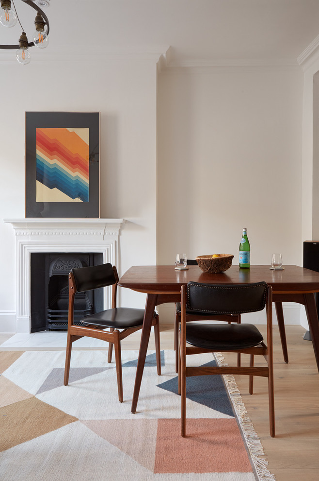 Inspiration for a mid-sized scandinavian dining room in London with white walls, light hardwood floors, a wood stove and a plaster fireplace surround.