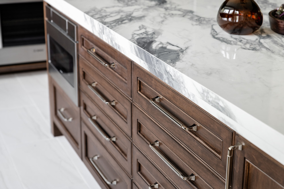 Large transitional u-shaped porcelain tile and white floor open concept kitchen photo in Vancouver with an undermount sink, recessed-panel cabinets, dark wood cabinets, quartz countertops, white backsplash, ceramic backsplash, stainless steel appliances, an island and white countertops