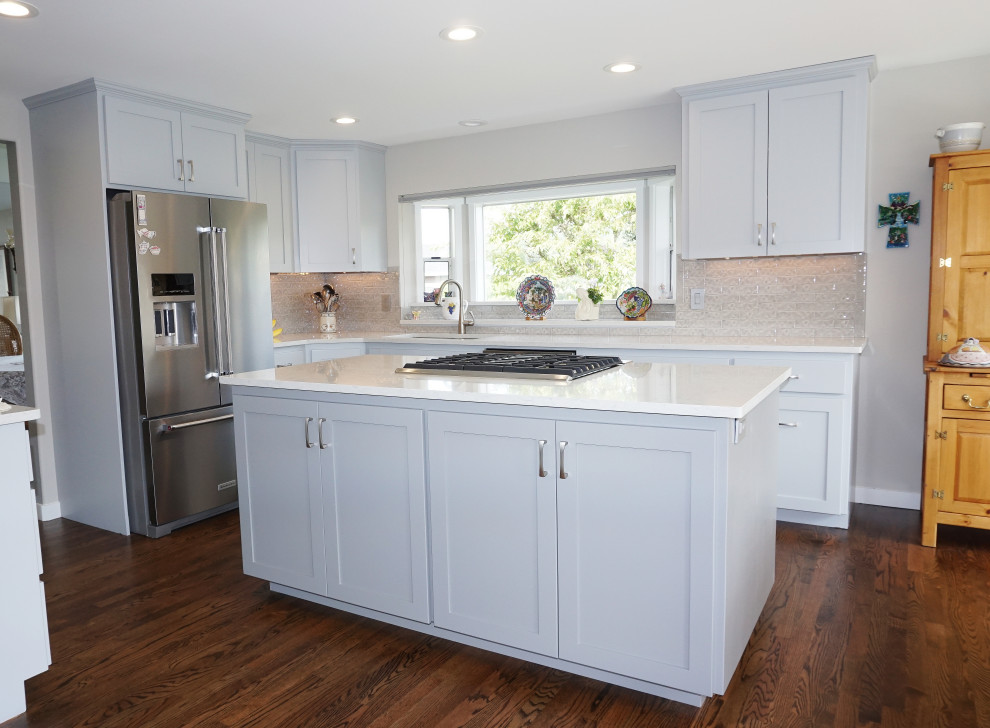 Design ideas for a mid-sized traditional eat-in kitchen in Seattle with an undermount sink, flat-panel cabinets, grey cabinets, quartzite benchtops, grey splashback, porcelain splashback, stainless steel appliances, medium hardwood floors, with island, brown floor and white benchtop.