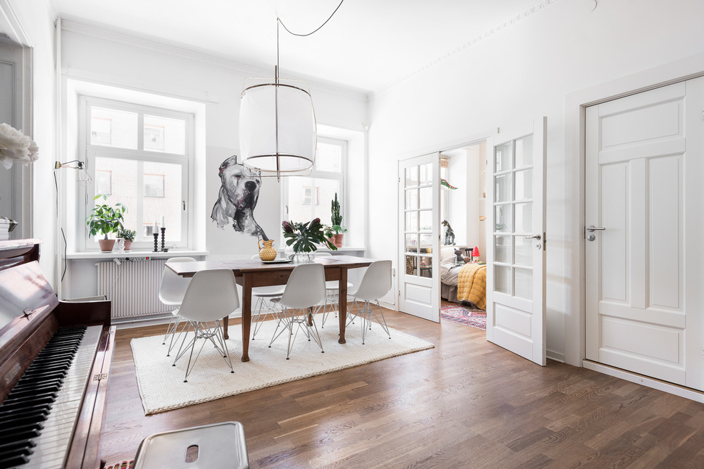 This is an example of a large scandinavian open plan dining in Gothenburg with white walls, medium hardwood floors and no fireplace.