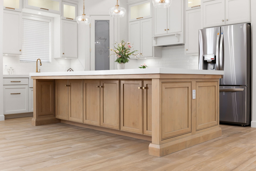 Laundry room - mid-sized transitional l-shaped light wood floor and brown floor laundry room idea in Austin with a farmhouse sink, flat-panel cabinets, white cabinets, quartz countertops, white backsplash, ceramic backsplash, white walls and white countertops