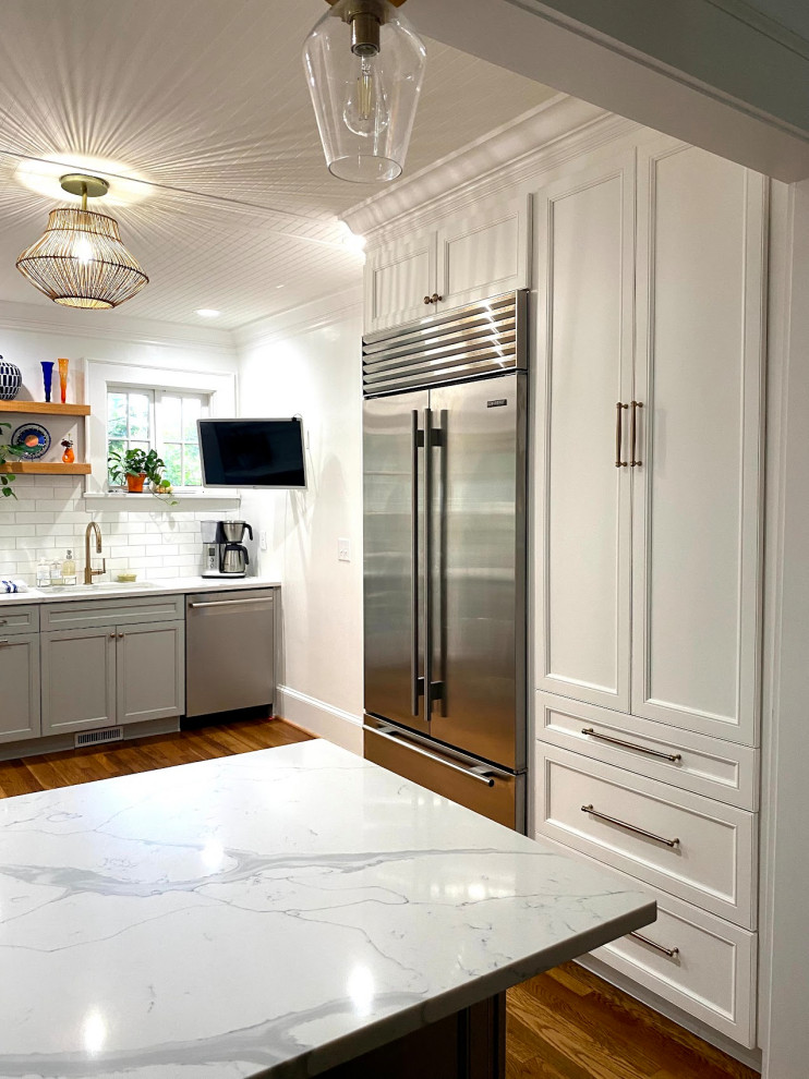 Foto på ett litet vintage vit kök, med en undermonterad diskho, bänkskiva i kvarts, vitt stänkskydd, stänkskydd i marmor, mellanmörkt trägolv och brunt golv