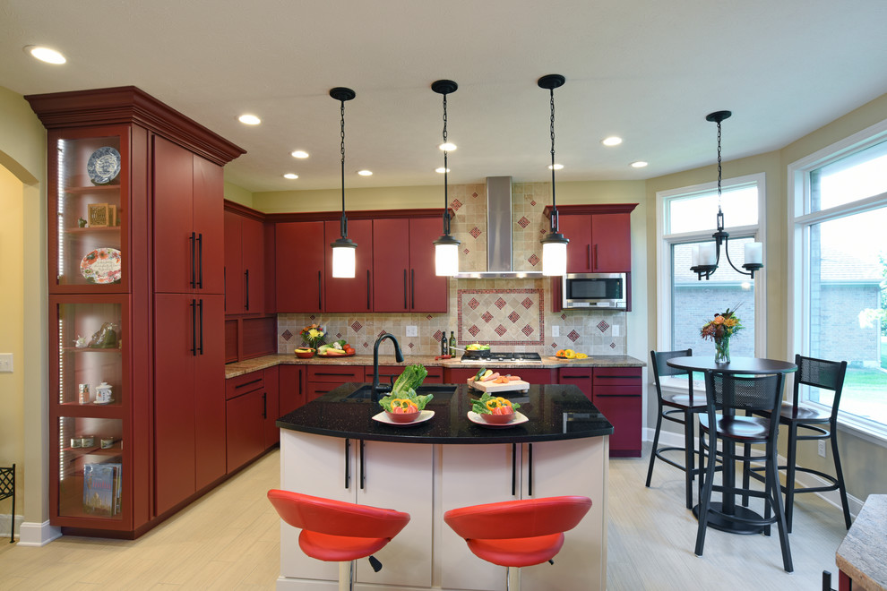 Inspiration for a large transitional porcelain tile and beige floor enclosed kitchen remodel with an undermount sink, flat-panel cabinets, red cabinets, granite countertops, beige backsplash, travertine backsplash, stainless steel appliances and an island