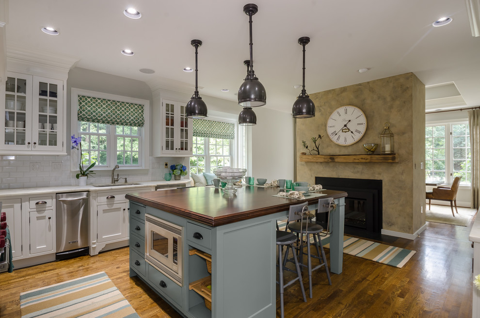 Large traditional eat-in kitchen in New York with an undermount sink, shaker cabinets, white cabinets, marble benchtops, white splashback, ceramic splashback, stainless steel appliances, dark hardwood floors and with island.