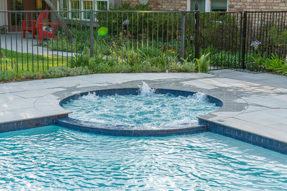 Exempel på en klassisk njurformad pool på baksidan av huset, med naturstensplattor