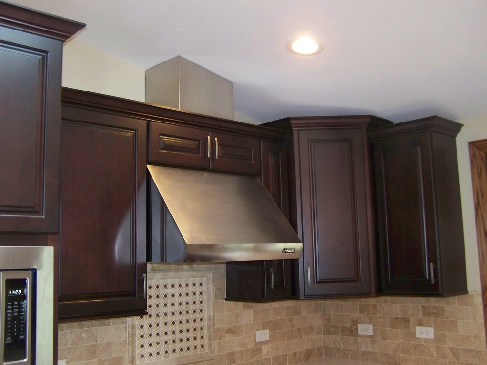 Huge elegant l-shaped medium tone wood floor open concept kitchen photo in Chicago with an undermount sink, raised-panel cabinets, dark wood cabinets, quartz countertops, beige backsplash, subway tile backsplash, stainless steel appliances and an island