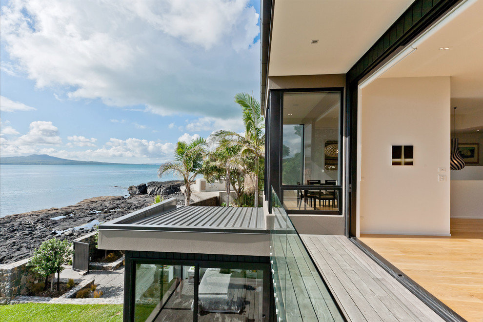 Large contemporary backyard deck in Auckland with a roof extension.