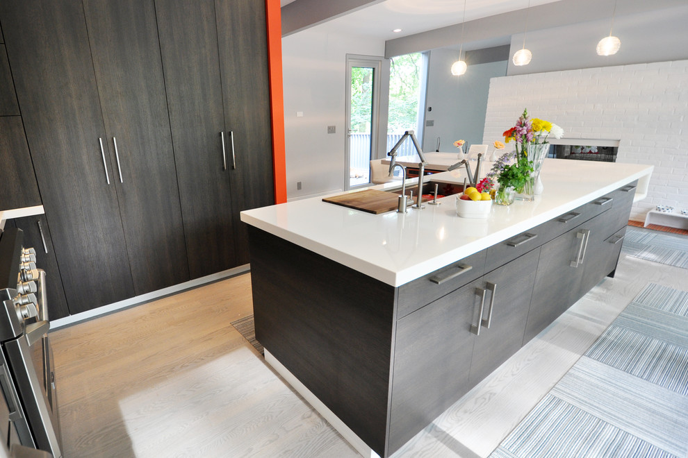 This is an example of a mid-sized modern eat-in kitchen in New York with a drop-in sink, flat-panel cabinets, dark wood cabinets, quartzite benchtops, grey splashback, glass tile splashback, stainless steel appliances, medium hardwood floors and with island.
