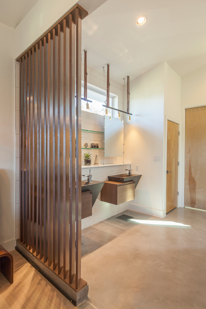 Design ideas for a mid-sized modern master bathroom in Austin with open cabinets, medium wood cabinets, an open shower, a two-piece toilet, white tile, porcelain tile, white walls, concrete floors, a wall-mount sink and solid surface benchtops.