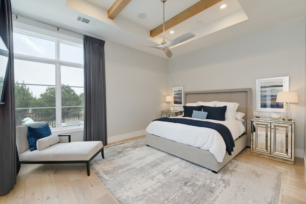 Modelo de dormitorio principal tradicional renovado grande con paredes grises, suelo de madera clara, suelo beige y vigas vistas