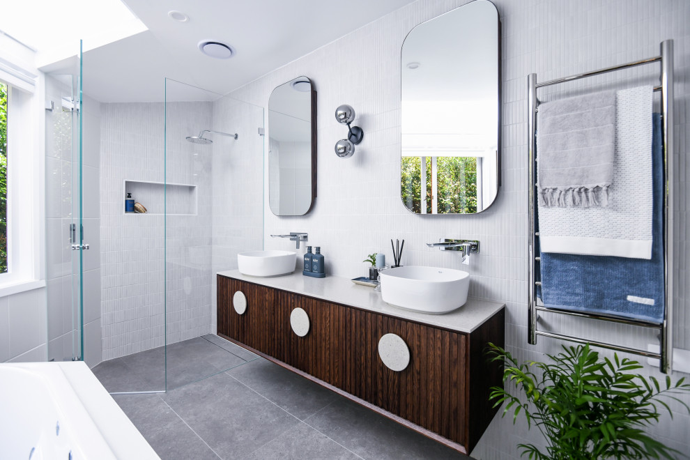 Inspiration for a medium sized contemporary ensuite bathroom in Sydney with freestanding cabinets, dark wood cabinets, a corner bath, a corner shower, yellow tiles, mosaic tiles, yellow walls, porcelain flooring, a vessel sink, solid surface worktops, grey floors, a hinged door, beige worktops, a wall niche, double sinks and a floating vanity unit.