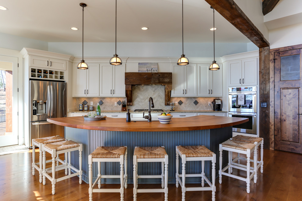 Design ideas for a large country open plan kitchen in Raleigh with white cabinets, wood benchtops, beige splashback, ceramic splashback, stainless steel appliances, medium hardwood floors, with island, shaker cabinets and brown floor.