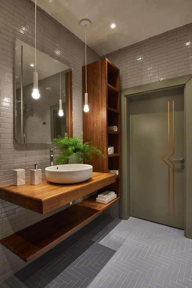 Contemporary 3/4 wet room bathroom in Moscow with a vessel sink, wood benchtops, grey floor, open cabinets, medium wood cabinets, gray tile, subway tile, grey walls, an open shower and brown benchtops.