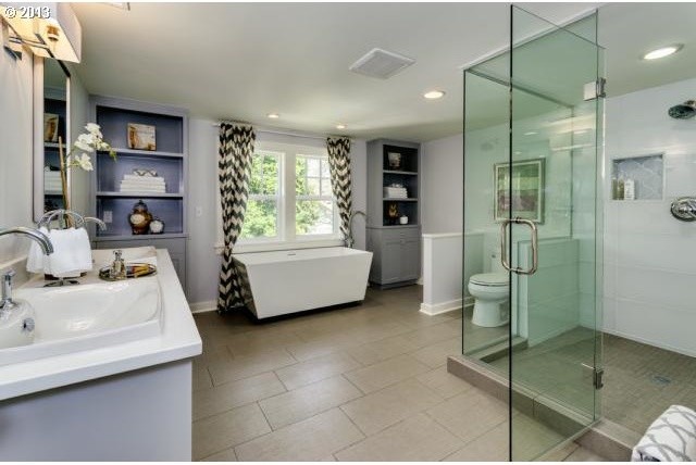 Design ideas for a large contemporary master bathroom in Portland with a drop-in sink, recessed-panel cabinets, grey cabinets, engineered quartz benchtops, a freestanding tub, a corner shower, a two-piece toilet, gray tile, glass tile, grey walls and porcelain floors.