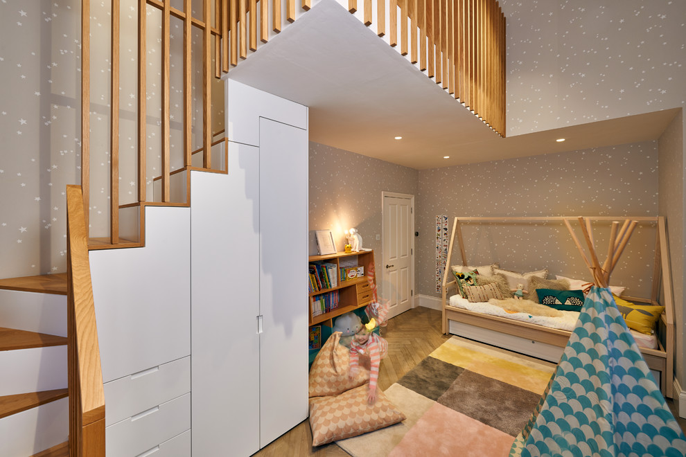 Idée de décoration pour une chambre de bébé fille design de taille moyenne avec un mur gris et un sol en bois brun.