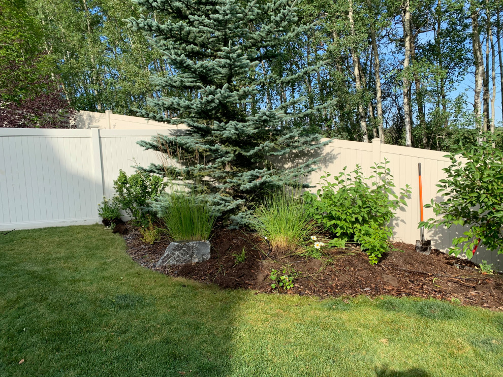 Foto di un piccolo giardino classico esposto in pieno sole dietro casa in estate con pacciame e recinzione in PVC