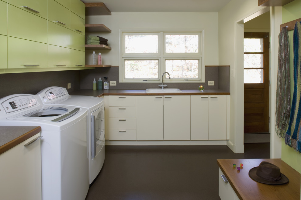 Midcentury laundry room in DC Metro with green cabinets and brown floor.