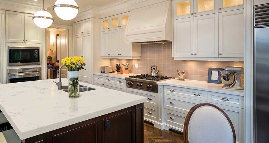 Enclosed kitchen - mid-sized transitional l-shaped medium tone wood floor enclosed kitchen idea in Boston with an undermount sink, beaded inset cabinets, white cabinets, marble countertops, white backsplash, subway tile backsplash, stainless steel appliances and an island