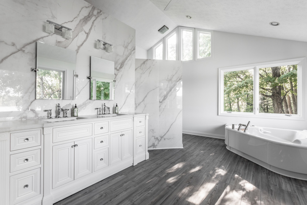 Inspiration for an expansive modern master bathroom in Indianapolis with furniture-like cabinets, white cabinets, a corner tub, an open shower, white tile, porcelain tile, white walls, vinyl floors, an undermount sink, marble benchtops, grey floor, a hinged shower door and white benchtops.