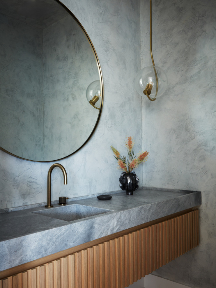 Cette image montre un WC et toilettes minimaliste en bois brun de taille moyenne avec un lavabo intégré, un plan de toilette en marbre, un mur gris, un plan de toilette gris et meuble-lavabo suspendu.
