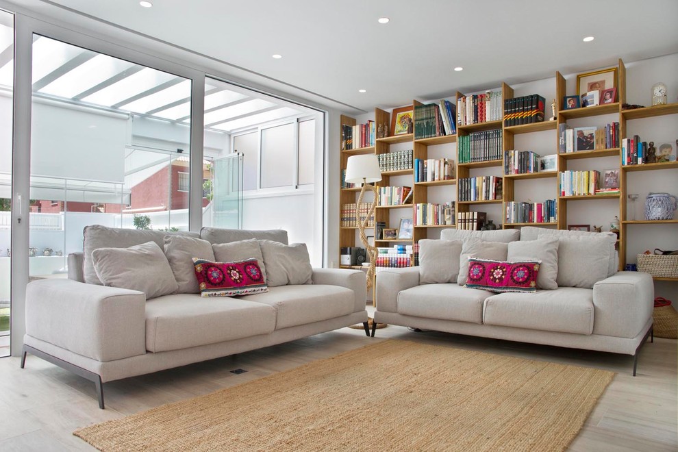 Photo of a contemporary living room in Other with a library, white walls, light hardwood floors and beige floor.