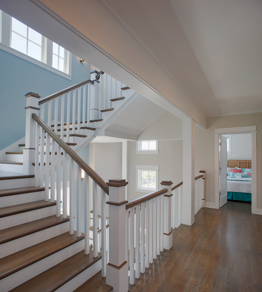 This is an example of a mid-sized beach style wood u-shaped staircase in Charleston with painted wood risers and wood railing.