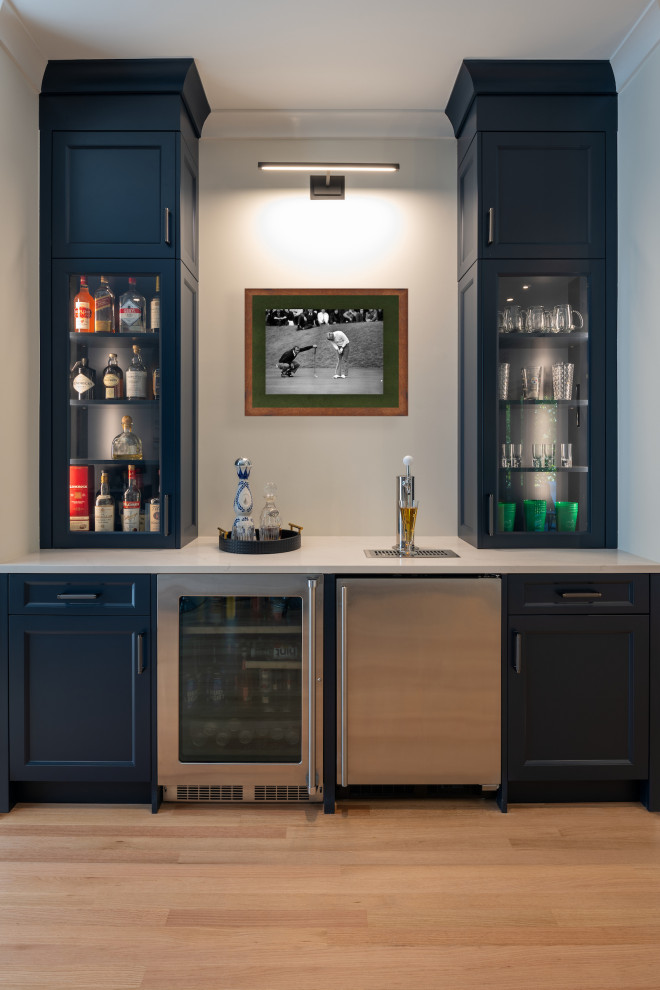 Imagen de bar en casa con barra de bar clásico grande con armarios estilo shaker, puertas de armario azules, encimera de madera, suelo de madera clara, suelo verde y encimeras blancas