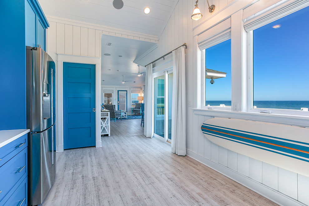 Design ideas for a mid-sized beach style l-shaped eat-in kitchen in Other with shaker cabinets, blue cabinets, limestone benchtops and vinyl floors.