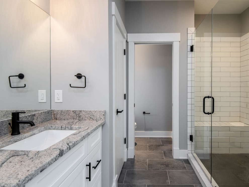 Design ideas for a large country master bathroom in Other with shaker cabinets, white cabinets, an alcove shower, a one-piece toilet, white tile, subway tile, grey walls, porcelain floors, an undermount sink, granite benchtops, grey floor, a hinged shower door and grey benchtops.