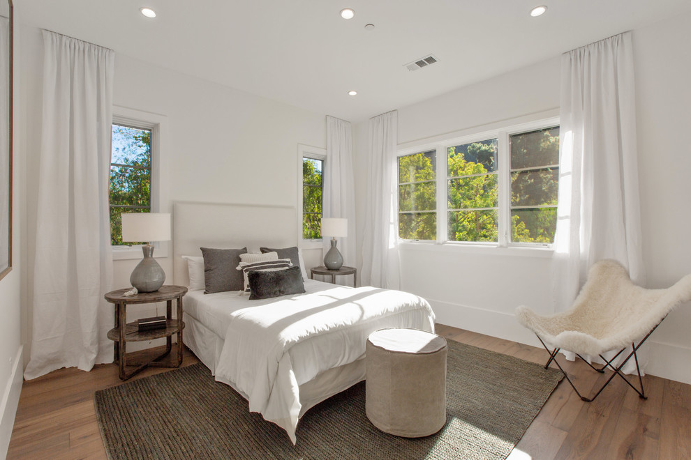 Inspiration for a transitional bedroom in Los Angeles with white walls, medium hardwood floors and brown floor.