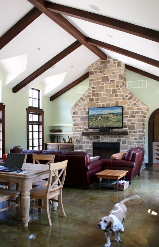 Country open concept living room in St Louis with concrete floors, a standard fireplace, a stone fireplace surround and a wall-mounted tv.